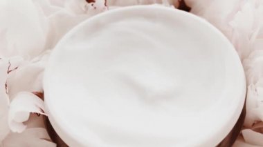 Yaşlanma önleyici yüz kremi kavanozu ve şakayık çiçekleri, lüks kozmetik ürünleri, güzellik ürünleri ve cilt ürünleri için cilt bakım rutini olarak temiz nemlendirici.