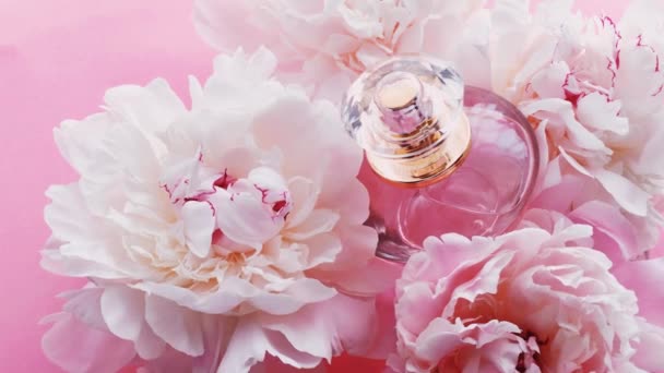 Roze parfumflesje met pioenachtige bloemen, chique geur als luxe cosmetische, mode en beauty product achtergrond — Stockvideo