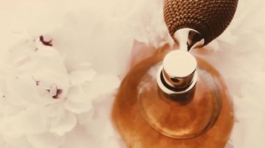 Şakayık çiçekli klasik parfüm şişesi, lüks kozmetik, retro moda ve güzellik ürünleri arka planında şık bir koku.