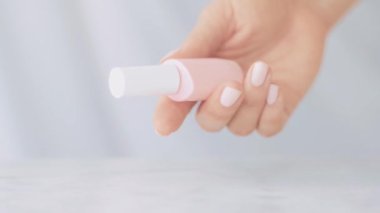 Doğal güzellik ürünü sahnesi, Fransız manikürü için kadın eli ve tırnak cilası şişeleri mermer masa üzerinde renkli pastel oje, makyaj ve kozmetik marka.