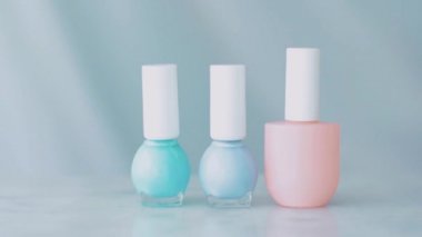 Pastel güzellik ürünü sahnesi, Fransız manikürü için kadın eli ve tırnak cilası şişeleri mermer masa üzerindeki renkli pastel oje, makyaj ve kozmetik marka.