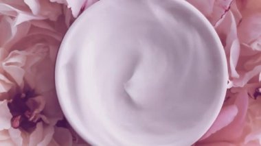 Mineral yüz kremi kavanozu ve şakayık çiçekleri, lüks kozmetik ürünleri, güzellik ürünleri ve cilt bakımı için temiz nemlendirici.