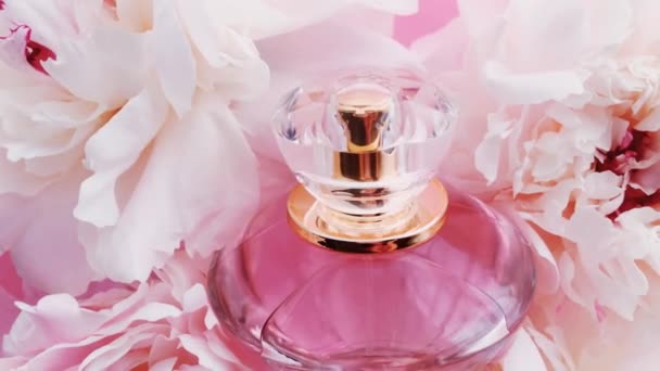 Roze parfumflesje met pioenachtige bloemen, chique geur als luxe cosmetische, mode en beauty product achtergrond — Stockvideo