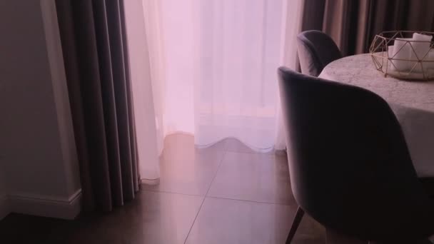 Vista de uma sala de jantar, mesa redonda, cadeiras e janela decorada com cortinas, móveis e design de interiores de luxo — Vídeo de Stock