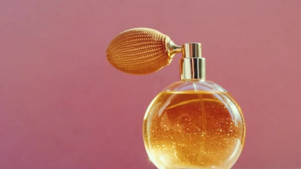 Luxuriöse goldene Parfümflasche und leuchtende Lichterketten auf rosa Hintergrund, glamouröser Duftduft als Parfümerieprodukt für Kosmetik- und Schönheitsmarken — Stockvideo