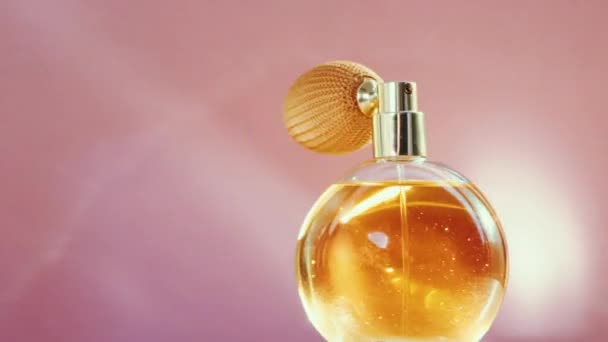 Frasco de perfume dorado de lujo y destellos de luz brillante sobre fondo rosa, aroma de fragancia glamorosa como producto de perfumería para la marca de cosméticos y belleza — Vídeos de Stock