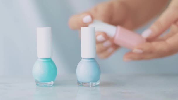 Cena de produto de beleza Pastel, mãos femininas e garrafas de esmalte para manicure francês, esmalte de unhas pastel colorido na mesa de mármore, maquiagem e marca de cosméticos — Vídeo de Stock