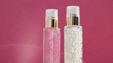 Şatafatlı cilt bakım ürünleri ve pembe arka planda parlak ışık parlamaları, makyaj malzemesi ve cilt bakımı rutini olarak serum jeli.