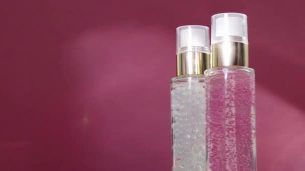Πολυτελή προϊόντα περιποίησης του δέρματος και λαμπερές φωτεινές φωτοβολίδες σε ροζ φόντο, βάση μακιγιάζ και τζελ ορού ως ρουτίνα φροντίδας του δέρματος για καλλυντικά προσώπου και μάρκα ομορφιάς — Αρχείο Βίντεο