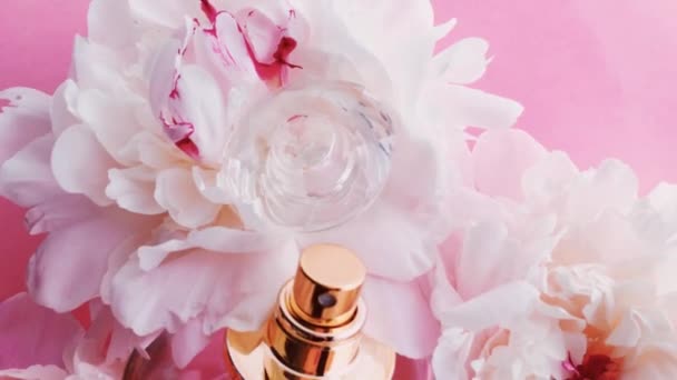 Roze parfumflesje met pioenachtige bloemen, chique geur als luxe cosmetische, mode en beauty product achtergrond — Stockvideo