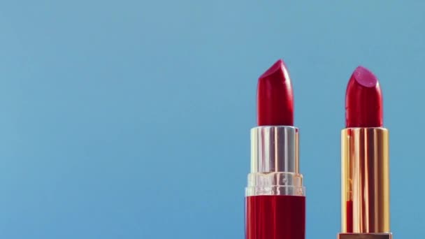 Zwei schicke rote Lippenstifte auf blauem Hintergrund und leuchtende Lichterketten, Luxus-Make-up-Produkt und Urlaubskosmetik für Beauty-Marken — Stockvideo