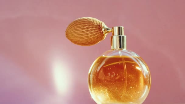 Frasco de perfume dorado de lujo y destellos de luz brillante sobre fondo rosa, aroma de fragancia glamorosa como producto de perfumería para la marca de cosméticos y belleza — Vídeos de Stock