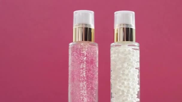 Produtos de cuidados com a pele de luxo e clarões brilhantes em fundo rosa, base de maquiagem e gel de soro como rotina de cuidados com a pele para cosméticos faciais e marca de beleza — Vídeo de Stock