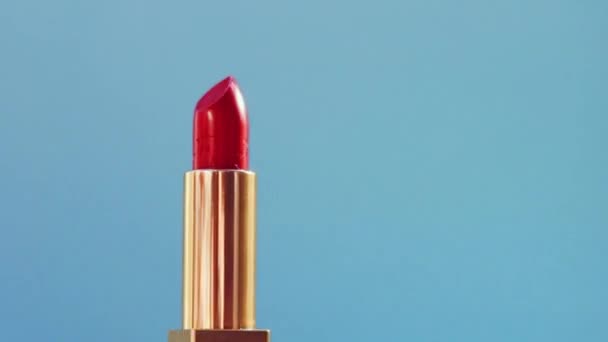 Elegante lápiz labial rojo en tubo dorado sobre fondo azul y destellos de luz brillante, producto de maquillaje de lujo y cosméticos navideños para la marca de belleza — Vídeo de stock