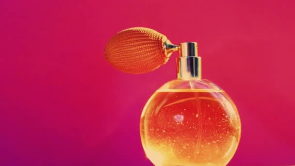 Garrafa de fragrância dourada e clarões brilhantes no fundo rosa, perfume glamouroso como produto de perfumaria de férias para marca de cosméticos e beleza — Vídeo de Stock