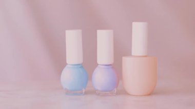 Pembe güzellik ürünü sahnesi, Fransız manikürü için kadın eli ve tırnak cilası şişeleri mermer masa üzerindeki renkli pastel oje, makyaj ve kozmetik marka.