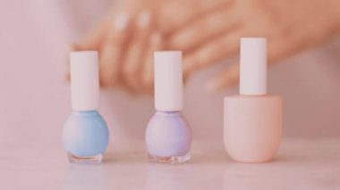 Pembe güzellik ürünü sahnesi, Fransız manikürü için kadın eli ve tırnak cilası şişeleri mermer masa üzerindeki renkli pastel oje, makyaj ve kozmetik marka.