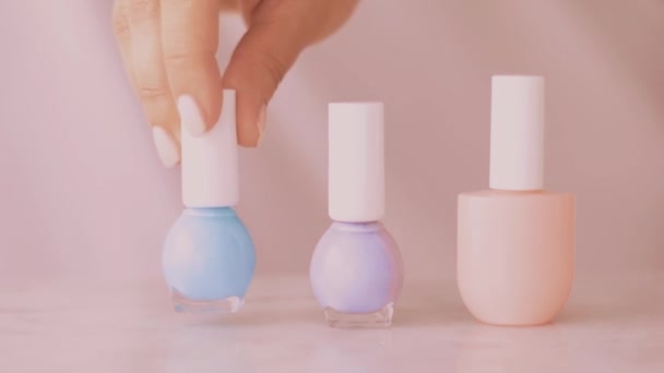 Cena de produto de beleza rosa, mãos femininas e garrafas de esmalte para manicure francês, esmalte de unha pastel colorido na mesa de mármore, maquiagem e marca cosmética — Vídeo de Stock