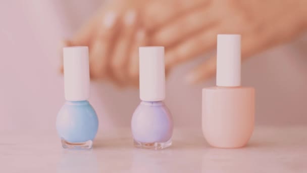 Рожевий косметичний продукт сцени, жіночі руки і пляшки нігтів для французького манікюру, барвистий пастельний лак для нігтів на мармуровому столі, макіяж і косметичний бренд — стокове відео