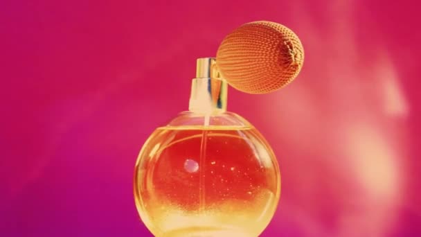 Garrafa de fragrância dourada e clarões brilhantes no fundo rosa, perfume glamouroso como produto de perfumaria de férias para marca de cosméticos e beleza — Vídeo de Stock