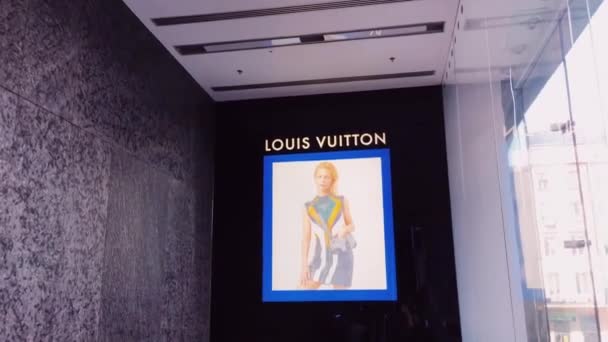 Publicidad de Louis Vuitton exhibida en tienda boutique, marca de moda y artículos de cuero y experiencia de compras de lujo — Vídeos de Stock