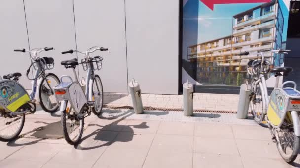 Услуги по обмену велосипедами в европейском городе, велосипеды припаркованы на улице — стоковое видео