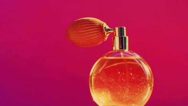 Frasco de fragancia dorada y destellos de luz brillante sobre fondo rosa, aroma de perfume glamoroso como producto de perfumería de vacaciones para la marca de cosméticos y belleza — Vídeo de stock