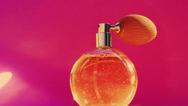 Gyllene doftflaska och lysande ljus blossar på rosa bakgrund, glamorös parfym doft som semester parfymeri produkt för kosmetiska och skönhet varumärke — Stockvideo