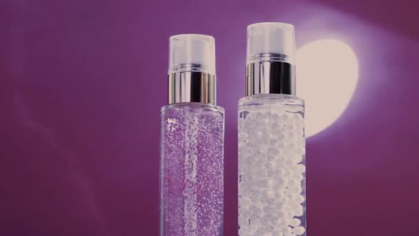 Base de maquillaje y gel de suero como productos de cuidado de la piel de lujo y bengalas de luz brillante sobre fondo púrpura, rutina de cuidado de la piel para cosméticos faciales y marca de belleza — Vídeo de stock