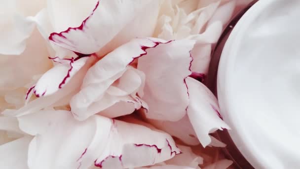 Biologische gezichtscrème pot en pioenroos bloemen, schone vochtinbrengende crème als huidverzorging routine voor luxe cosmetische, beauty product en huidverzorgingsmerk — Stockvideo