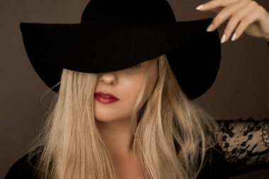 Şapka takan zarif sarışın kadın moda kampanyası ve güzellik markası için sanatsal film portresi.