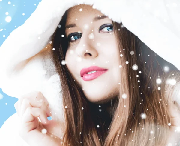 Natal e inverno férias retrato de jovem mulher de casaco de pele com capuz branco, neve no fundo azul, moda e estilo de vida — Fotografia de Stock