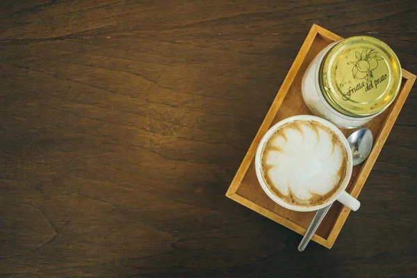 Filiżanka kawy i ziarna kawy na drewnianym stole w kawiarni — Zdjęcie stockowe