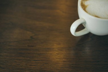 Kafede ahşap masada kahve bardağı ve kahve çekirdekleri