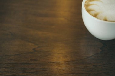 Kafede ahşap masada kahve bardağı ve kahve çekirdekleri