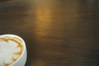 Kafede ahşap masada kahve bardağı ve kahve çekirdekleri