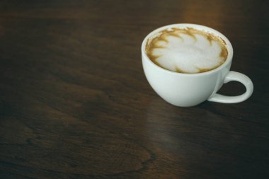 Kafede ahşap masada kahve bardağı ve kahve çekirdekleri