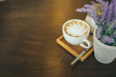 Kafede ahşap masada kahve bardağı ve kahve çekirdekleri