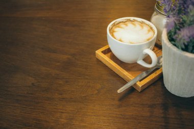 Kafede ahşap masada kahve bardağı ve kahve çekirdekleri