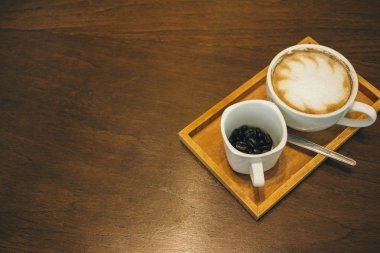 Kafede ahşap masada kahve bardağı ve kahve çekirdekleri