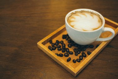 Kafede ahşap masada kahve bardağı ve kahve çekirdekleri