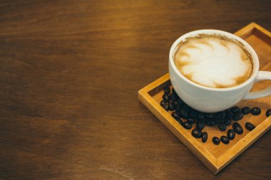 Kafede ahşap masada kahve bardağı ve kahve çekirdekleri