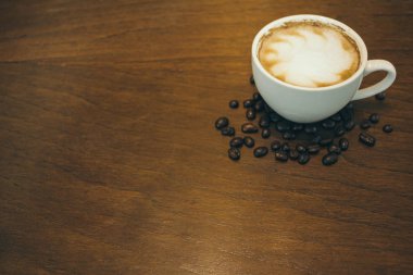 Kafede ahşap masada kahve bardağı ve kahve çekirdekleri