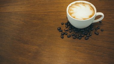 Kafede ahşap masada kahve bardağı ve kahve çekirdekleri