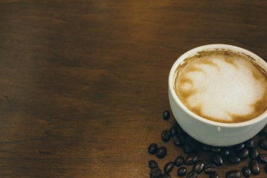 Kafede ahşap masada kahve bardağı ve kahve çekirdekleri