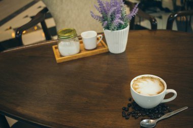Kafede ahşap masada kahve bardağı ve kahve çekirdekleri
