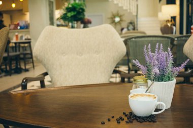 Kafede ahşap masada kahve bardağı ve kahve çekirdekleri