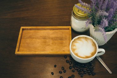 Kafede ahşap masada kahve bardağı ve kahve çekirdekleri
