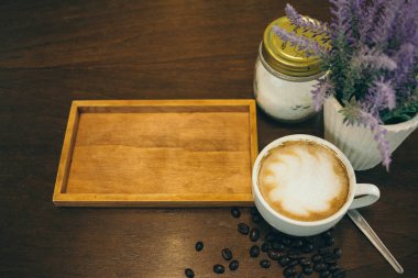 Kafede ahşap masada kahve bardağı ve kahve çekirdekleri