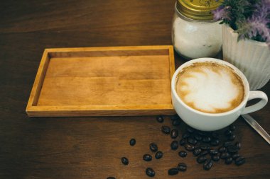 Kafede ahşap masada kahve bardağı ve kahve çekirdekleri